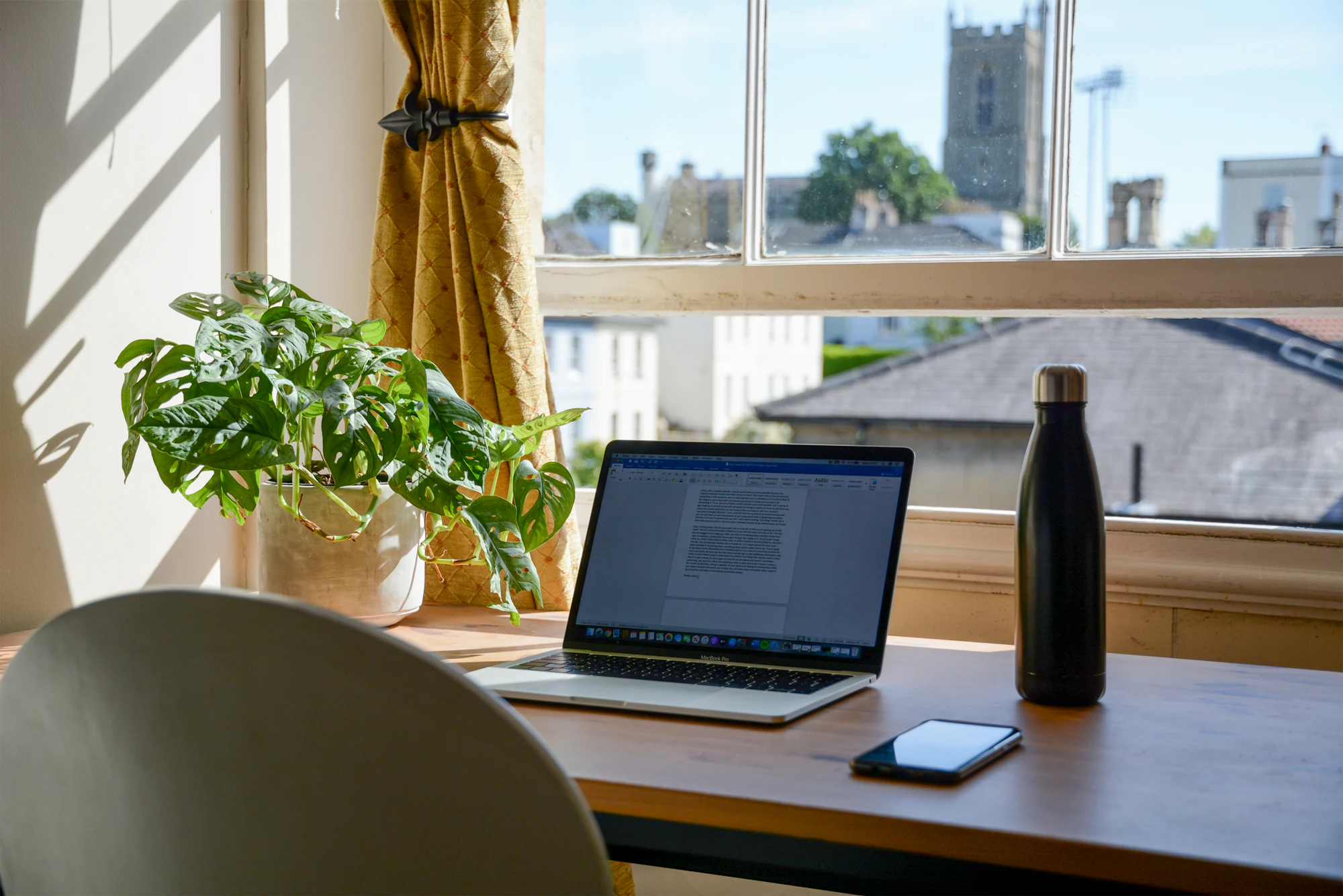 Laptop on a desk by a bright window