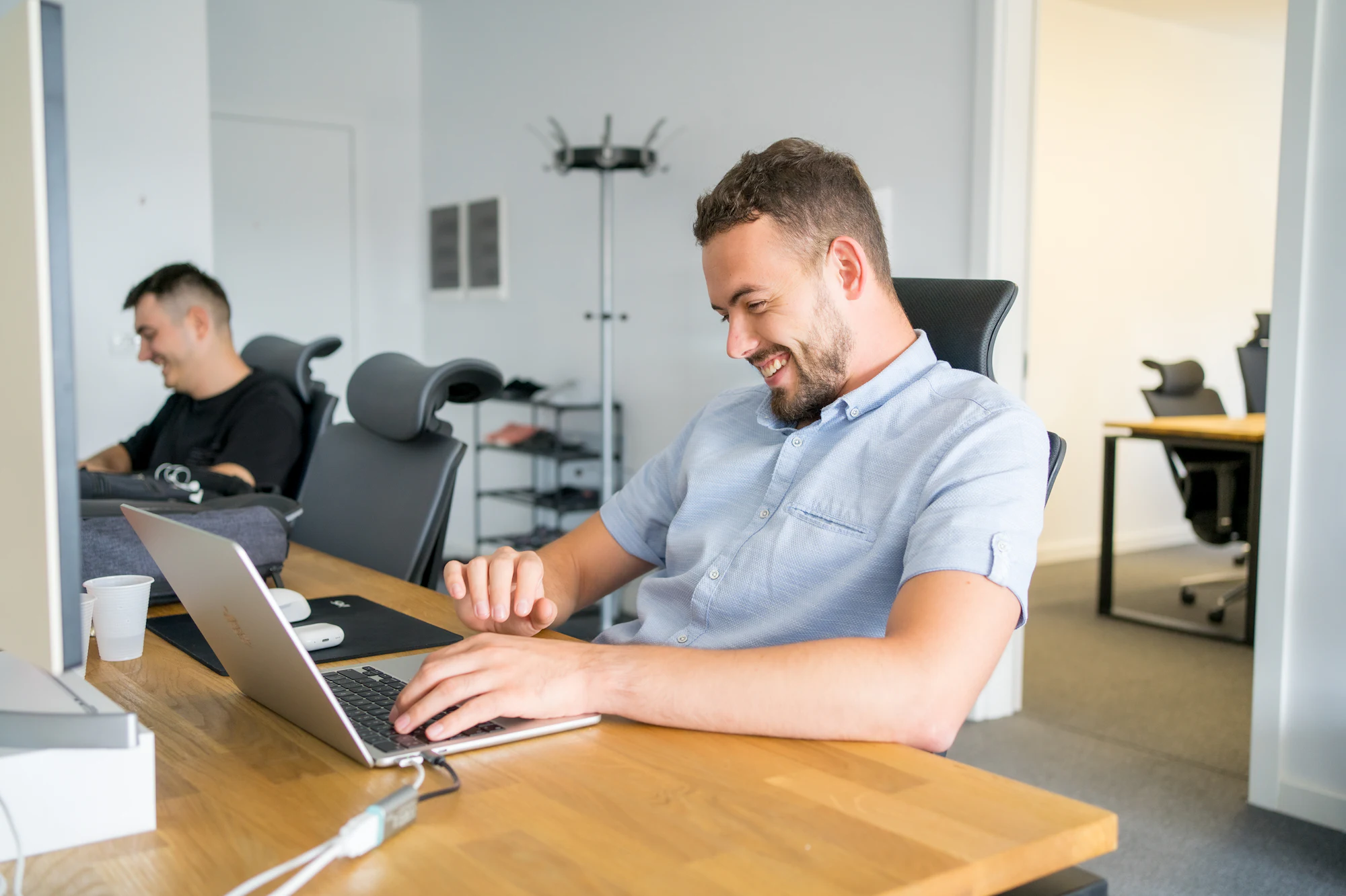 Smiling man working on a laptop in a bright office