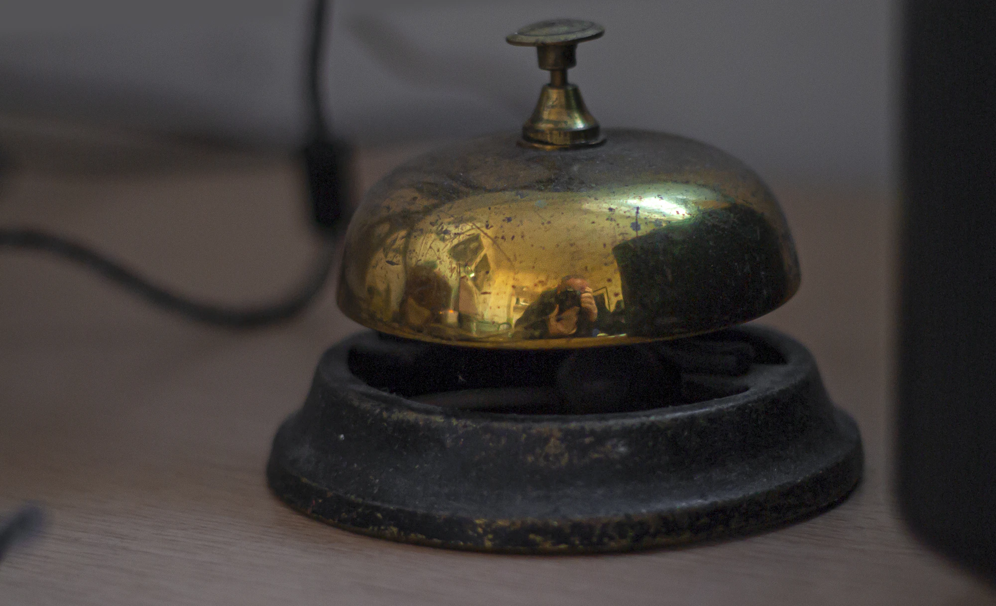 Brass service bell on a wooden hotel reception desk