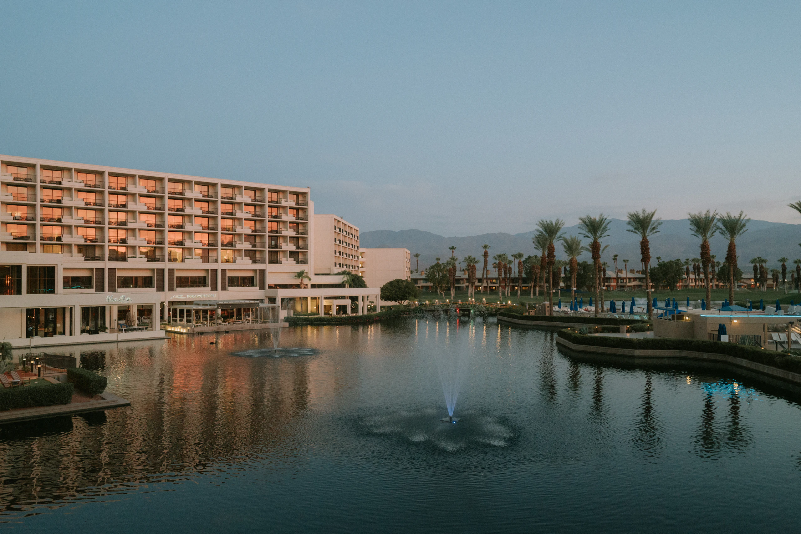 Resort hotel by a lake at dusk, rooms lit